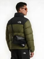 Back view of a model wearing an olive green puffer jacket with a black contrast shoulder panel.