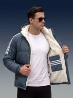 Man opening his slate blue winter jacket to reveal a thick white sherpa inner lining and a secure interior chest pocket