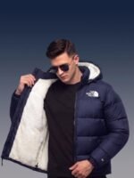 Male model wearing the unzipped navy sherpa puffer jacket, showing how the white sherpa lining contrasts with a black t-shirt.