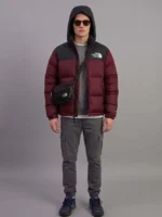 Front view of a model wearing a North Face inspired premium maroon puffer jacket with a black crossbody bag.