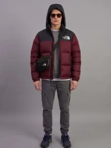 Front view of a model wearing a North Face inspired premium maroon puffer jacket with a black crossbody bag.