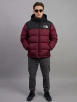 Man wearing a premium maroon puffer jacket with his hands in the pockets.