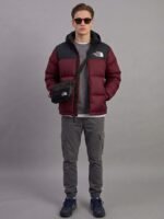 Full-length lifestyle shot of a stylish men's 700-down winter coat in maroon paired with grey cargo pants.